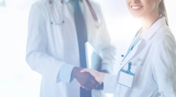 Dwoje uśmiechniętych młodych medyków ściskających dłonie w biurze. Lekarze. Praca zespołowa — Zdjęcie stockowe