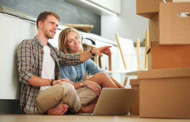 Genç bir çift yeni ev içinde hareket. Oturma ve açma sonra rahatlatıcı. Bir şey üstünde laptop arıyorum. Genç Çift