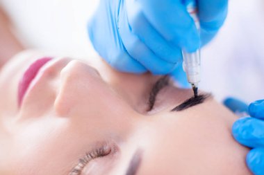 Kaşlar için kalıcı makyaj. Güzellik salonunda kalın kaşlı güzel bir kadın..