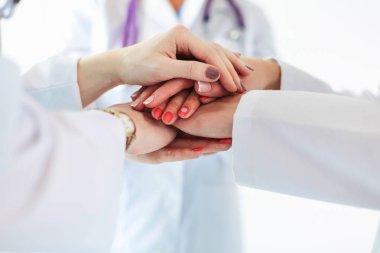 Doktorlar ve hemşireler tıbbi bir ekipte el ele tutuşuyorlar..