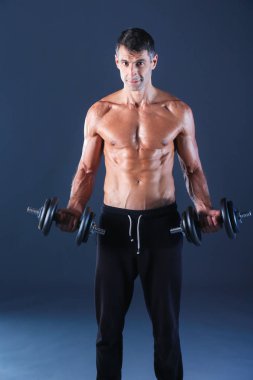 Yakışıklı kaslı adam dumbell ile çalışma dışarı. Kişisel fitness eğitmeni. Kişisel eğitim.