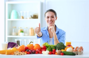 Ahşap iç kısımda meyve ve sebze dolu masada oturan genç ve tatlı bir kadın..