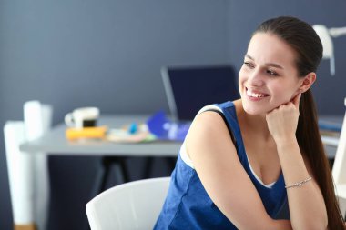 Masasında enstrümanlar, planlar ve dizüstü bilgisayarlarla oturan genç bir kadın..