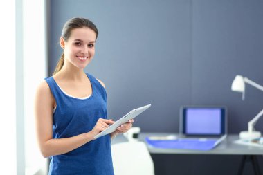 Masasında enstrümanlar, planlar ve dizüstü bilgisayarlarla oturan genç bir kadın..