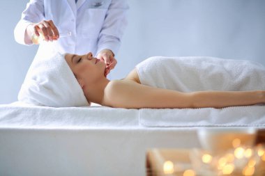 Masaj masasında uzanmış gözleri kapalı rahatlayan genç bir kadın. - Kadın. Spa salonu