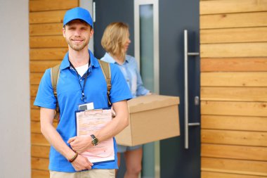 Mavi üniformalı gülümseyen kurye servis konseptine paket kutusu teslim eden teslimatçı. Mavi üniformalı gülümseyen teslimatçı.