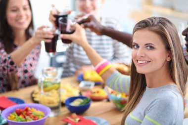 Ahşap masada otururken birlikte yemek yiyen bir grup insanın üst düzey görüntüsü. Masada yemek var. İnsanlar fast food yiyor. Bir kızın portresi.