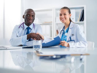 Ofiste tokalaşırken gülümseyen iki genç tıp adamı. Doktorlar. Takım çalışması.