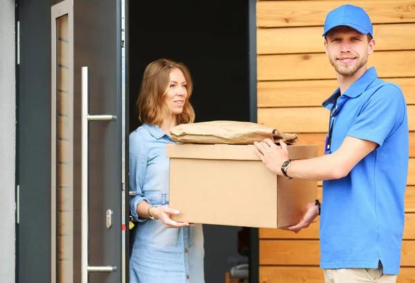 Leende leverans man i blå uniform leverera paket låda till mottagaren - kurir service koncept. Leende leverans man i blå uniform — Stockfoto