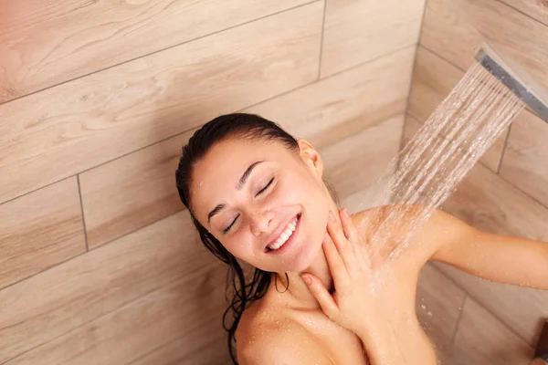 Jeune femme belle sous la douche dans la salle de bain . — Photo