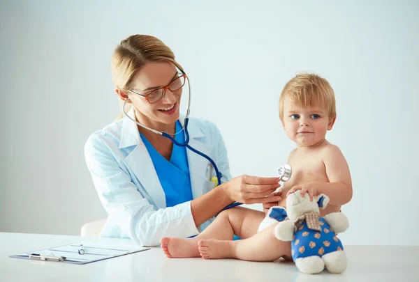 Ženský doktor poslouchá dítě se stetoskopem na klinice — Stock fotografie