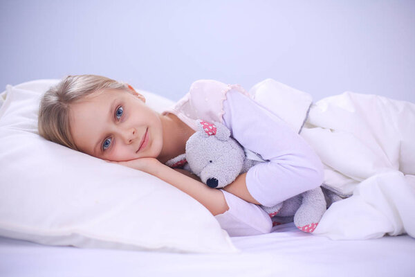 Child little girl sleeps in the bed with a toy teddy bear.