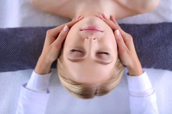 Mujer joven acostada en una mesa de masaje, relajándose con los ojos cerrados. Una mujer. Salón de spa —  Fotos de Stock