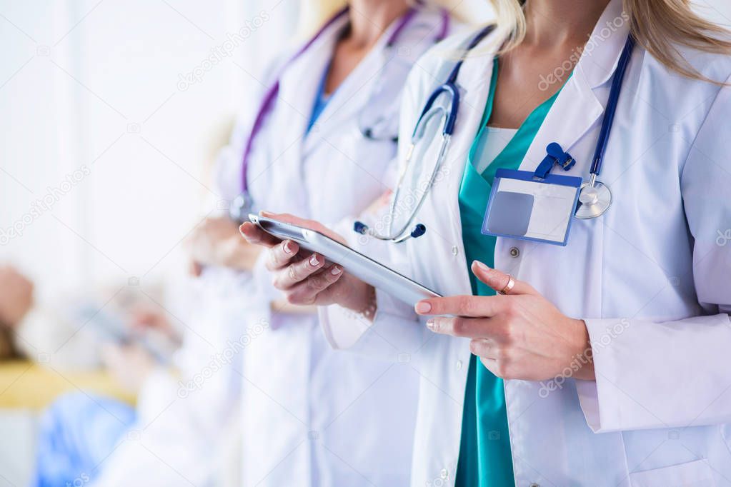 Portrait of three confident female doctors standing with arms crossed at the medical office.