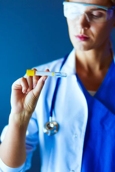 Medizinische oder wissenschaftliche Wissenschaftlerin oder Ärztin mit Blick auf ein Reagenzglas mit klarer Lösung in einem Labor oder Labor. — Stockfoto