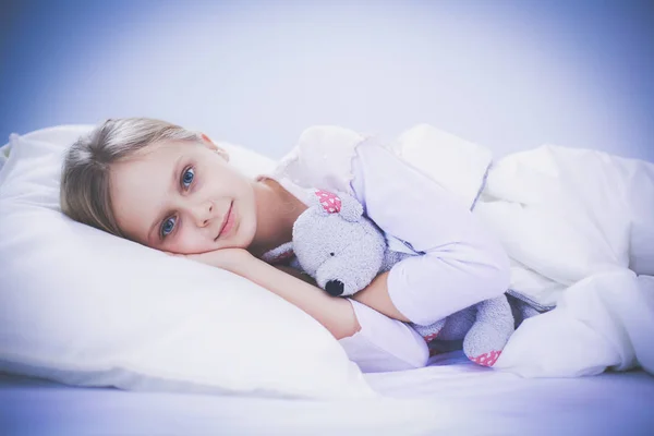 Barn lilla flicka sover i sängen med en leksak nallebjörn. — Stockfoto