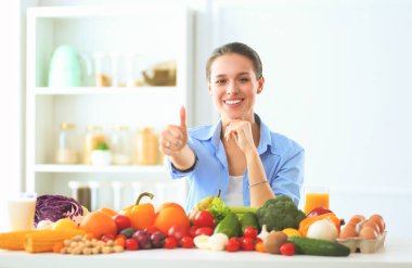 Ahşap iç kısımda meyve ve sebze dolu masada oturan genç ve tatlı bir kadın..