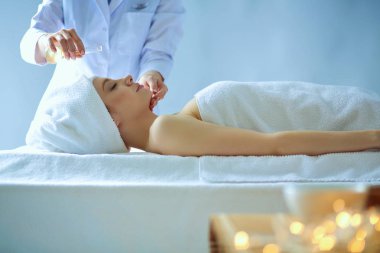 Masaj masasında uzanmış gözleri kapalı rahatlayan genç bir kadın. - Kadın. Spa salonu