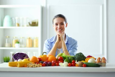 Ahşap iç kısımda meyve ve sebze dolu masada oturan genç ve tatlı bir kadın..