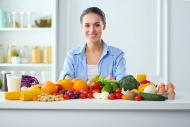 Ahşap iç kısımda meyve ve sebze dolu masada oturan genç ve tatlı bir kadın..