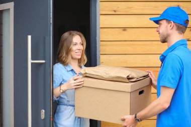 Mavi üniformalı gülümseyen kurye servis konseptine paket kutusu teslim eden teslimatçı. Mavi üniformalı gülümseyen teslimatçı.