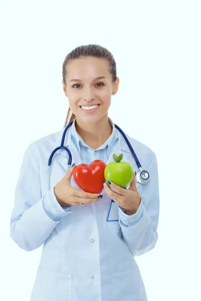 Piękna uśmiechnięta lekarka trzymająca czerwone serce i zielone jabłko. Kobieta lekarz — Zdjęcie stockowe