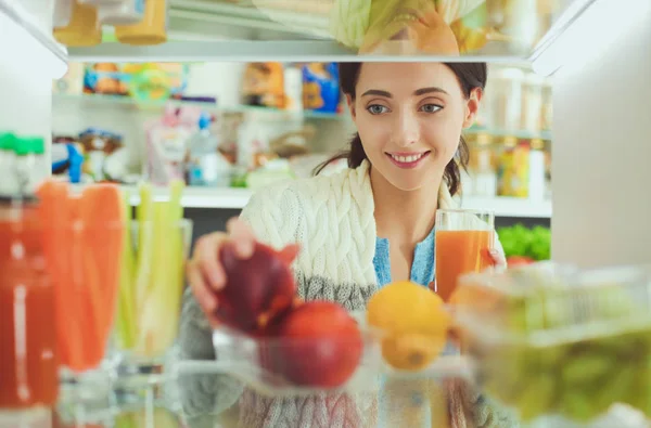 Portrait of female standing near open fridge full of healthy food, vegetables and fruits. Portrait of female — Stock Photo, Image