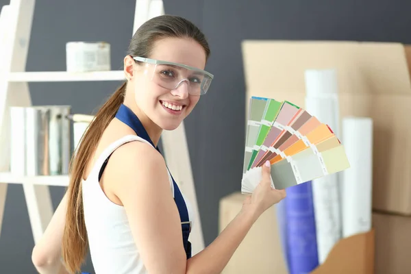 Young woman holding a color swatch with a painter painting . — Stock Photo, Image