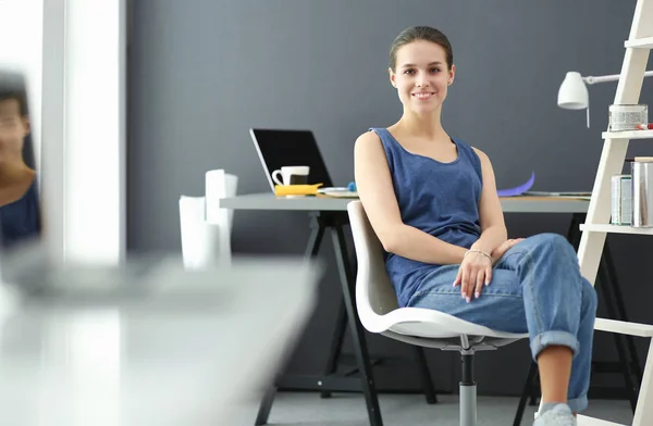 Młoda kobieta siedzi przy biurku z instrumentami, planem i laptopem. — Zdjęcie stockowe