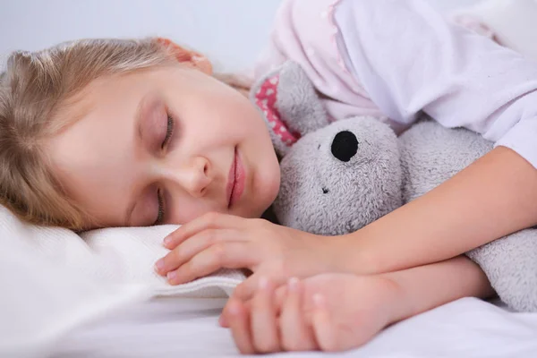 Bambino bambina dorme nel letto con un orsacchiotto giocattolo . — Foto Stock