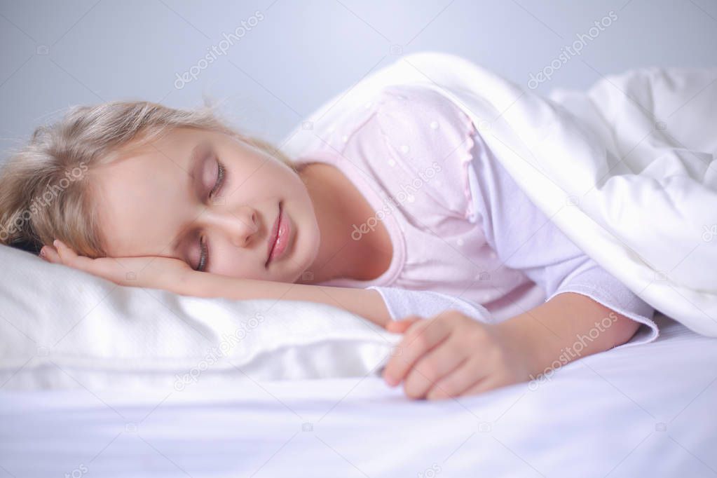 Child little girl sleeps in the bed with a toy teddy bear.