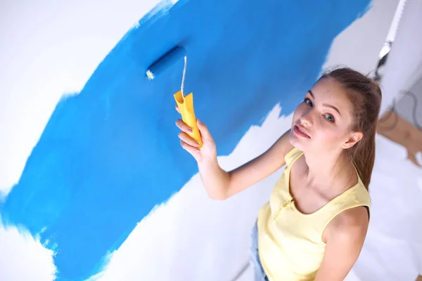 Feliz hermosa mujer joven haciendo pintura de pared, de pie cerca de la escalera —  Fotos de Stock