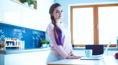 Cep telefonu ayakta modern mutfak kullanan kadın.