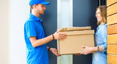 Mavi üniformalı gülümseyen kurye servis konseptine paket kutusu teslim eden teslimatçı. Mavi üniformalı gülümseyen teslimatçı.