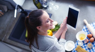 Güzel bir kadın mutfakta pasta pişiriyor. Masanın yanında duruyor..