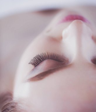 Masaj masasında uzanmış gözleri kapalı rahatlayan genç bir kadın. - Kadın. Spa salonu