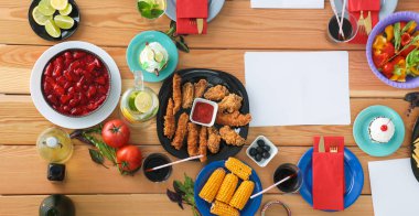 Ahşap masada otururken birlikte yemek yiyen bir grup insanın üst düzey görüntüsü. Masada yemek var. İnsanlar fast food yiyor..