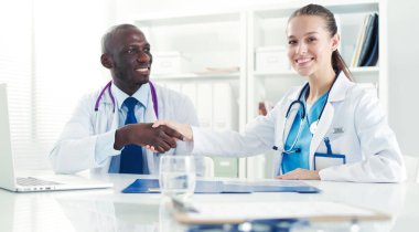 Ofiste tokalaşırken gülümseyen iki genç tıp adamı. Doktorlar. Takım çalışması.