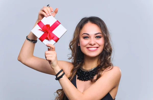 Jeune femme sourire heureux tenir boîte cadeau dans les mains, isolé sur fond gris — Photo