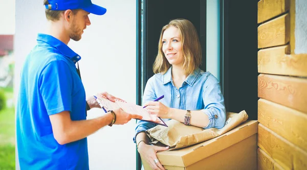 Mavi üniformalı gülümseyen kurye servis konseptine paket kutusu teslim eden teslimatçı. Mavi üniformalı gülümseyen teslimatçı.