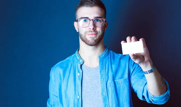 Jovem segurando um cartão de crédito de pé sobre fundo cinza. Jovem empresário. — Fotografia de Stock