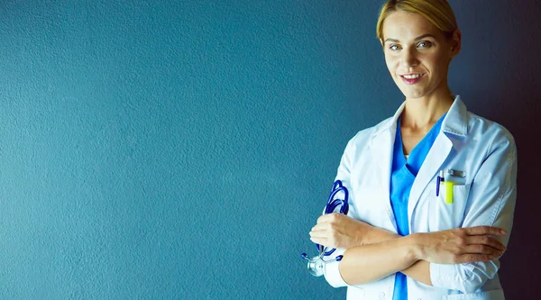 Portret van een jonge vrouwelijke arts met witte jas in het ziekenhuis. — Stockfoto