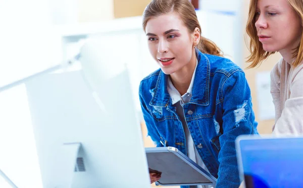 Due giovani donne in piedi vicino alla scrivania con strumenti, piano e laptop. — Foto Stock