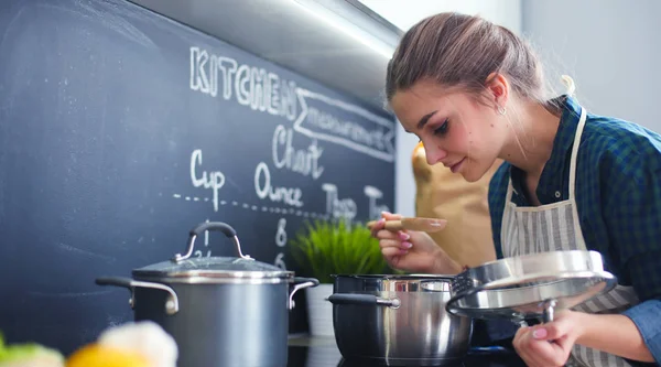 Junge Frau steht am Herd in der Küche . — Stockfoto