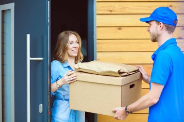 Mavi üniformalı gülümseyen kurye servis konseptine paket kutusu teslim eden teslimatçı. Mavi üniformalı gülümseyen teslimatçı.