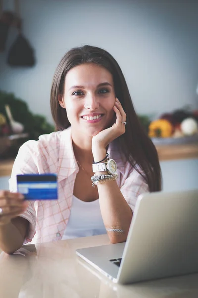 Mujer sonriente compras en línea utilizando tableta y tarjeta de crédito en la cocina. Mujer sonriente — Foto de Stock