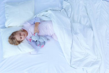 çocuk oyuncak oyuncak ayı ile yatakta uyur küçük kız.