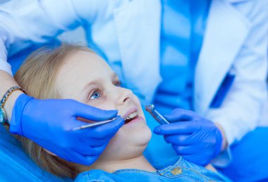 Küçük kız dişçi ofisinde oturuyor..