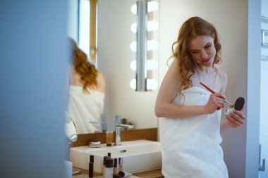 Telefon ile banyo üzerinde duran genç kadın.