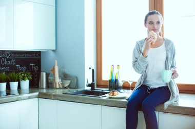 Mutfakta dijital tablet kullanan güzel genç bir kadın..